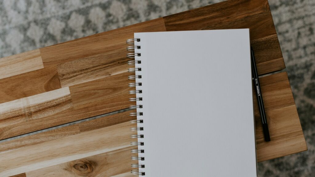 White spiral notebook on brown wooden table