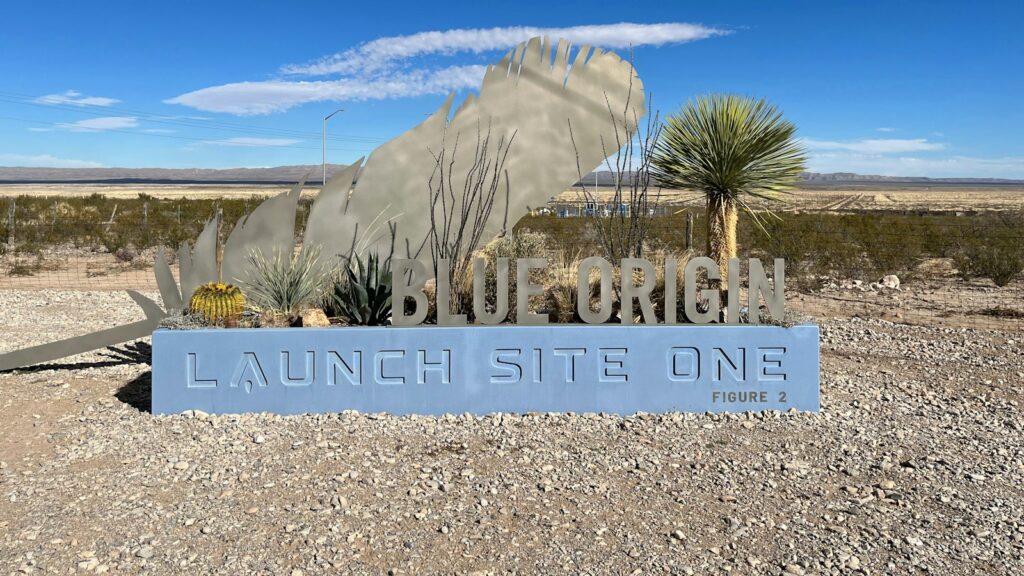 A sign in the middle of a desert with a sky background
