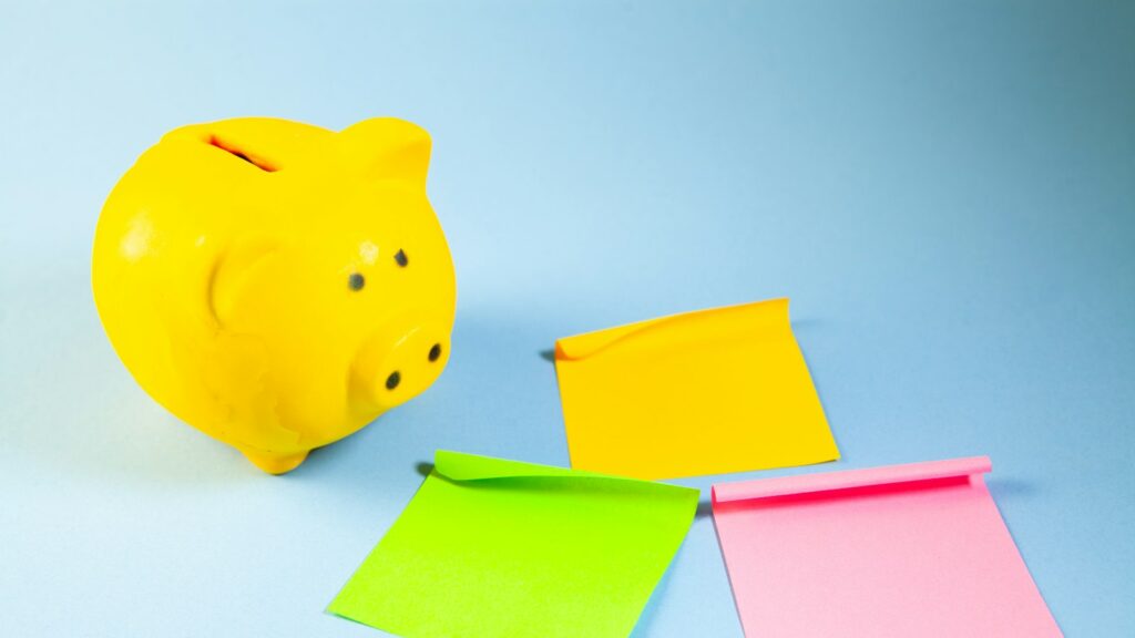 A yellow piggy bank with three colorful sticky notes