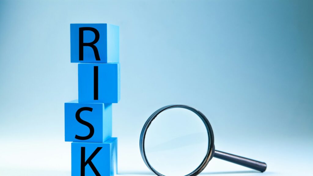 Blue blocks spelling risk next to a magnifying glass