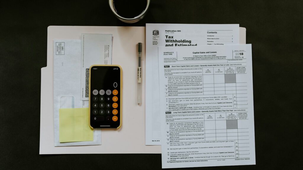 Black Android smartphone near ballpoint pen, tax withholding certificate on top of white folder