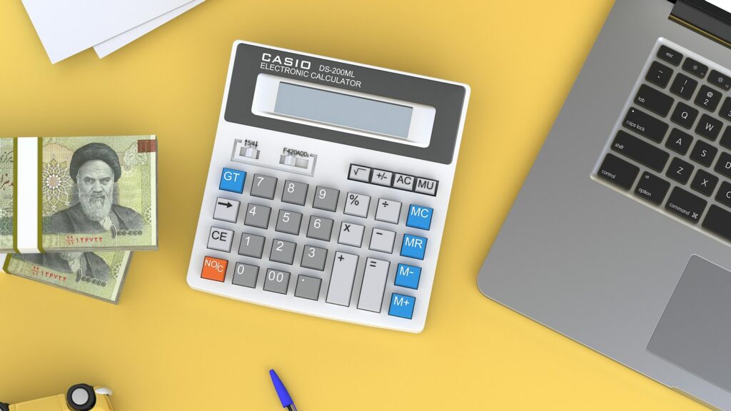 A calculator sitting on top of a desk next to a laptop
