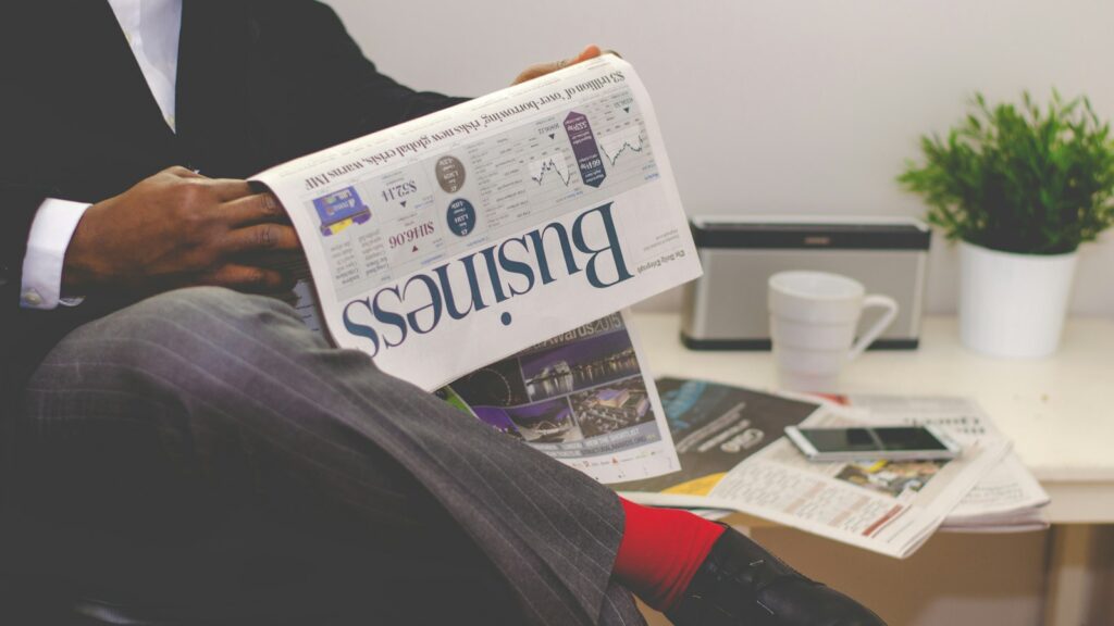 Person sitting near table holding newspaper