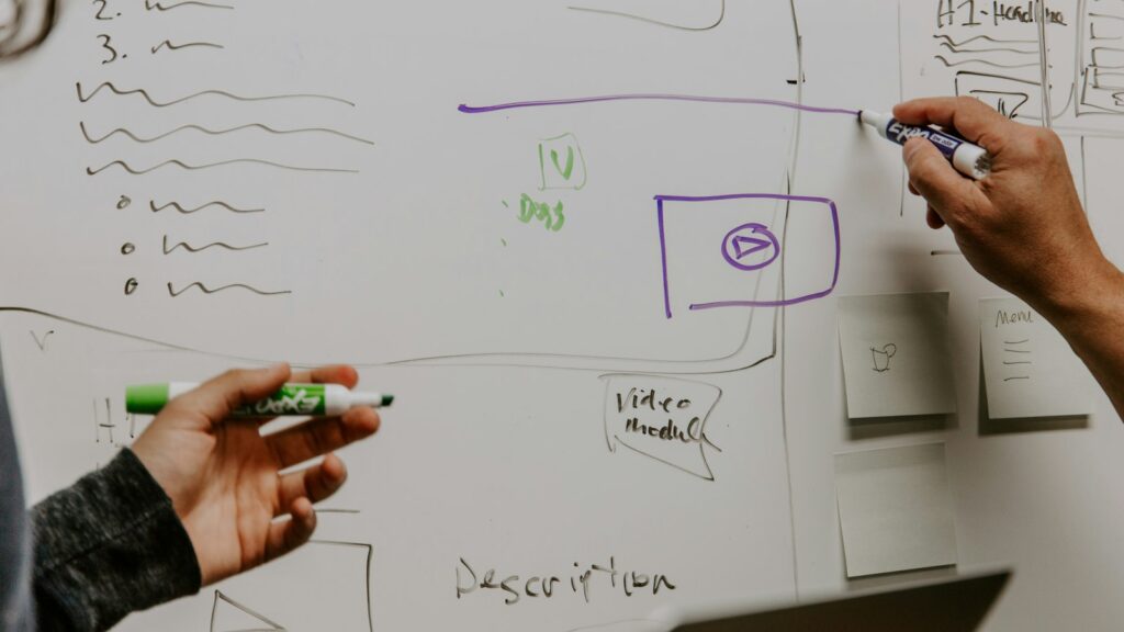 Two people drawing on whiteboard