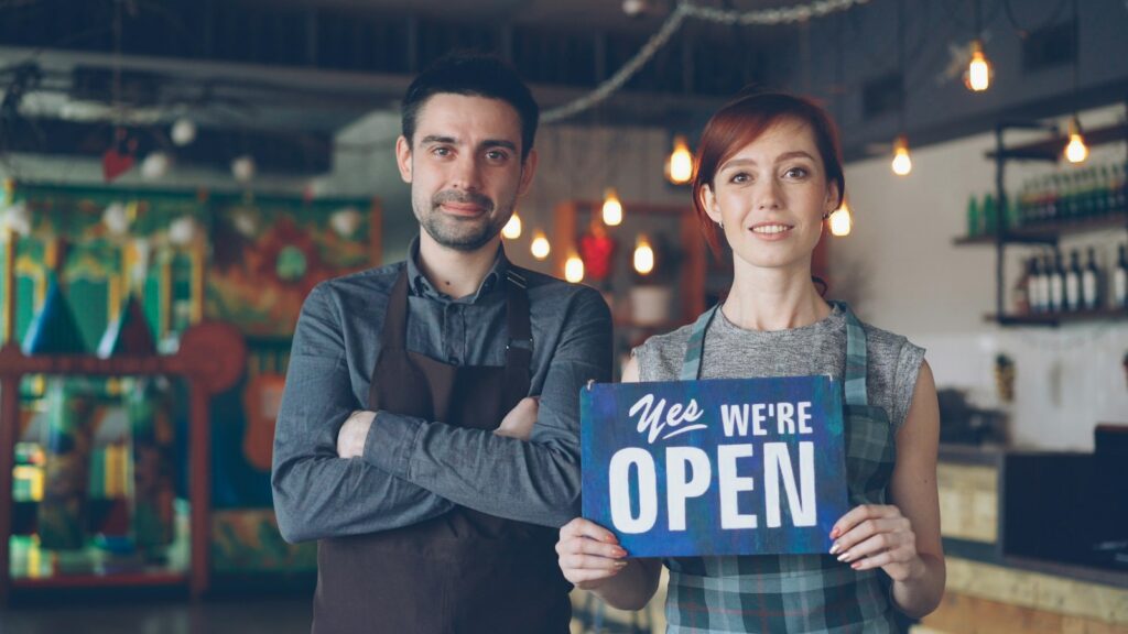 A happy couple welcomes customers: we are open
