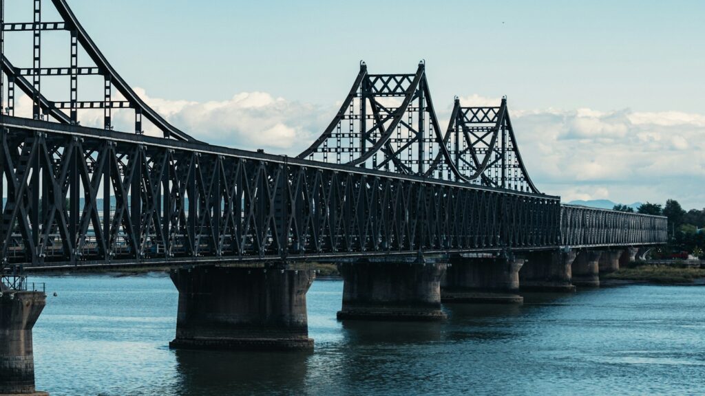 A large metal bridge spans a wide river