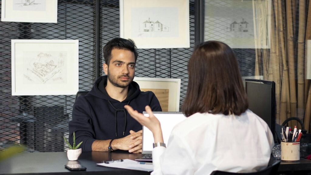 A man sitting at a desk talking to a woman