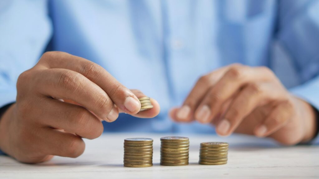 A person stacking coins on top of a table