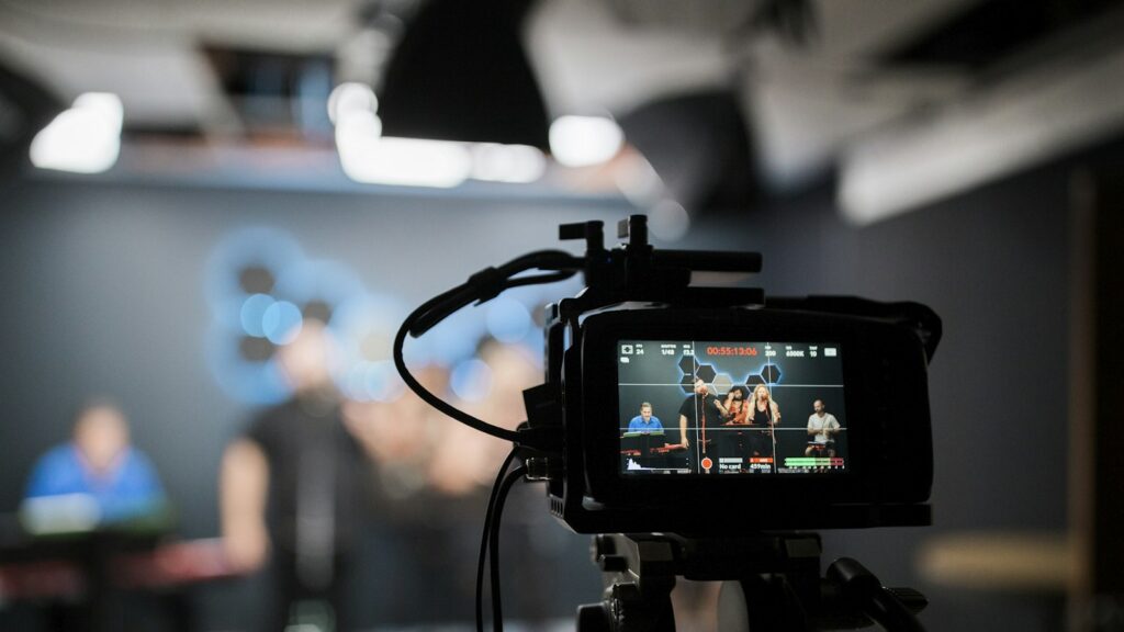 A professional video camera recording a musical group performing in a studio