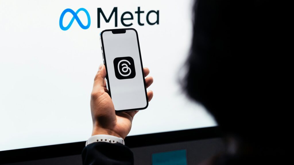 A person holding a cell phone in front of a large screen