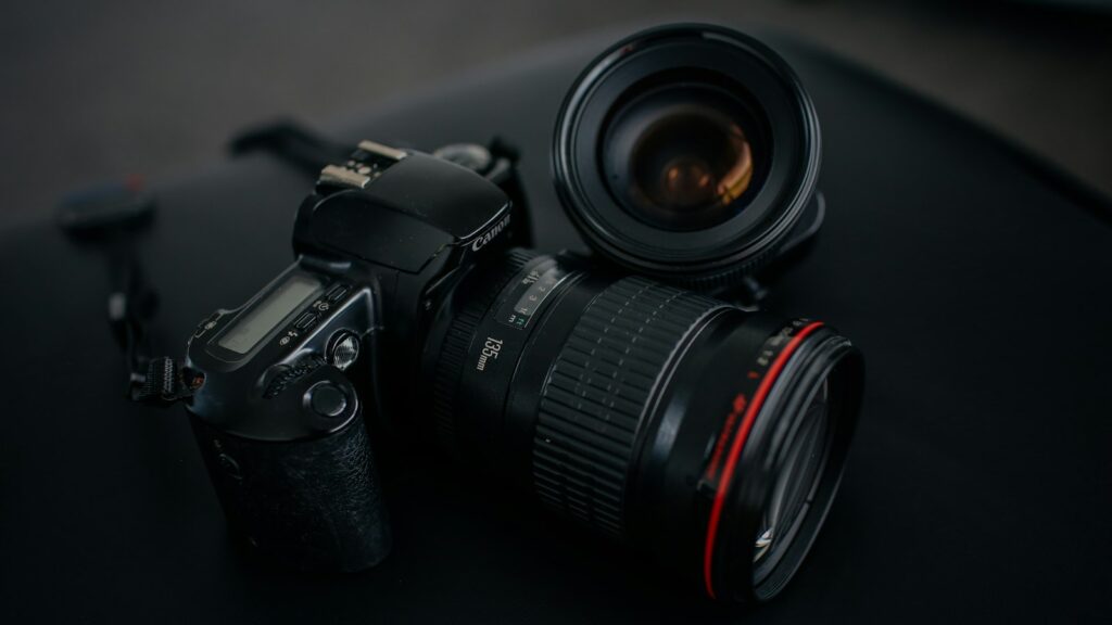 Black Canon DSLR camera beside camera lens