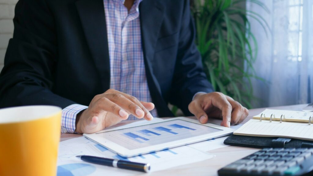 Person in black suit jacket holding white tablet computer