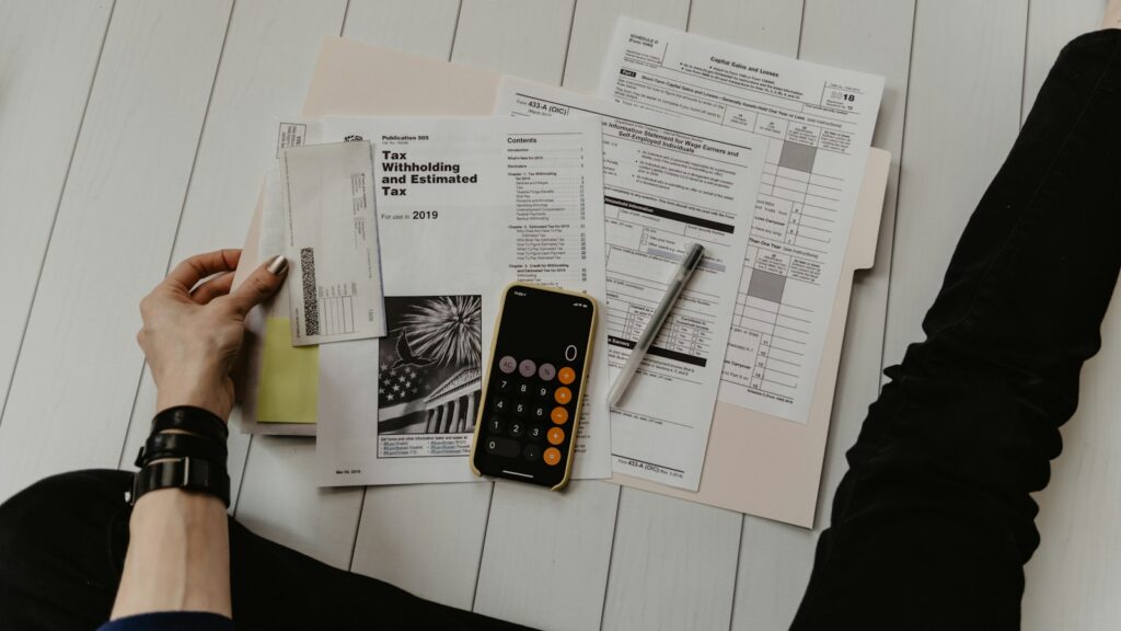 Person holding paper near pen and calculator