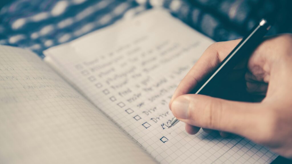 Person writing bucket list on book