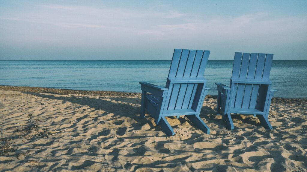 Two blue beach chairs near body of water