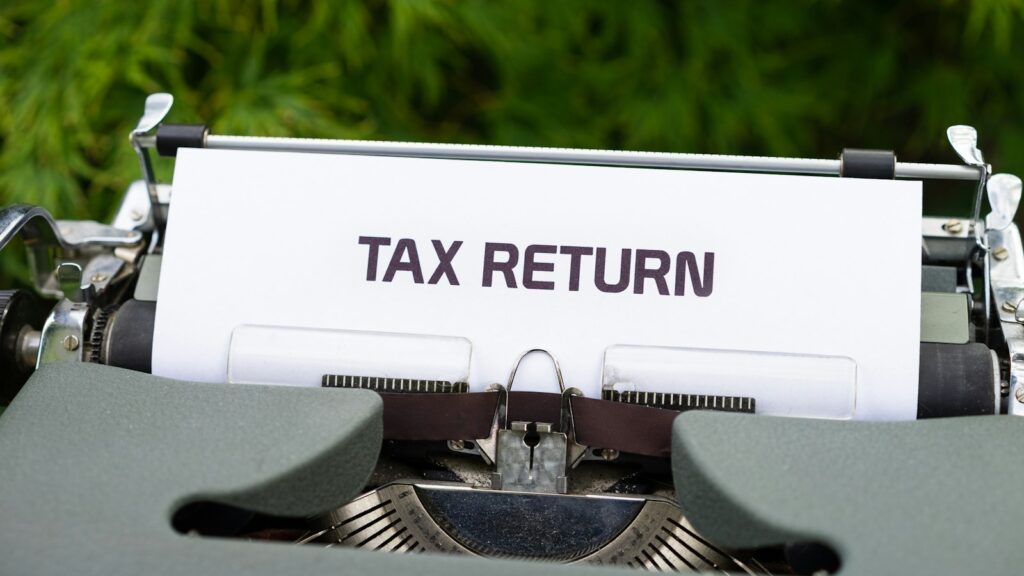 A close up of a typewriter with a tax return sign on it