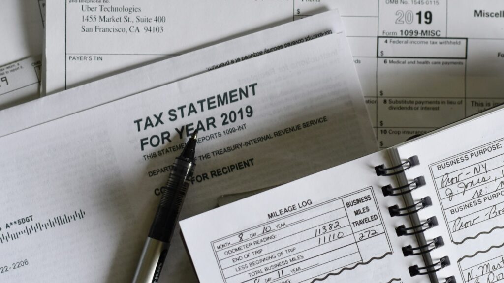 A pen resting on 2019 tax forms and a mileage log book