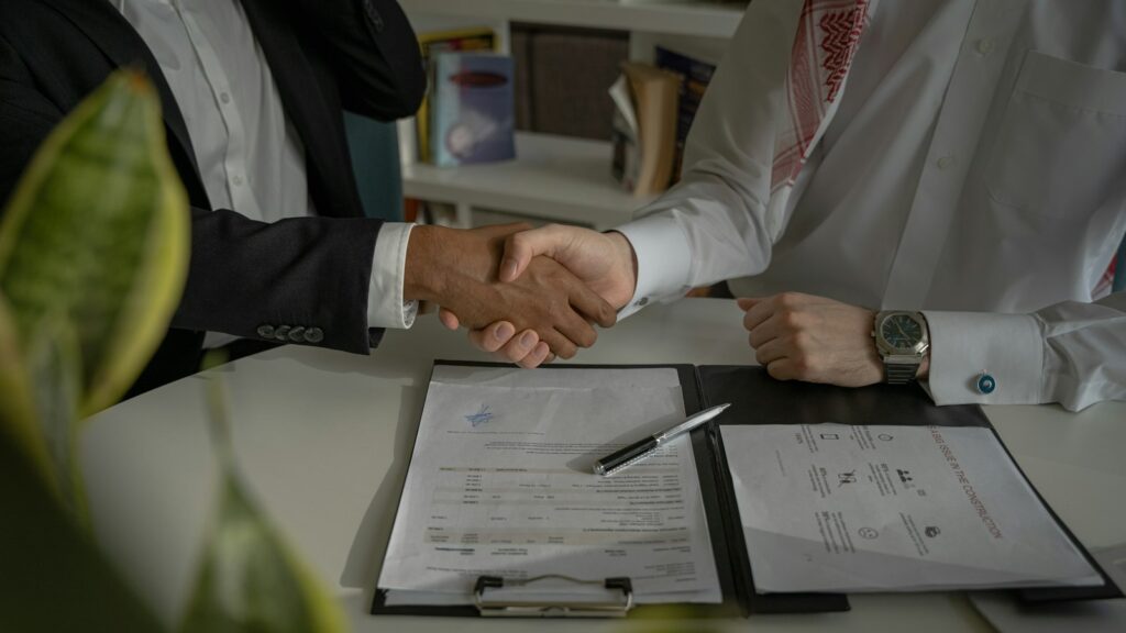 Two people shaking hands over a piece of paper