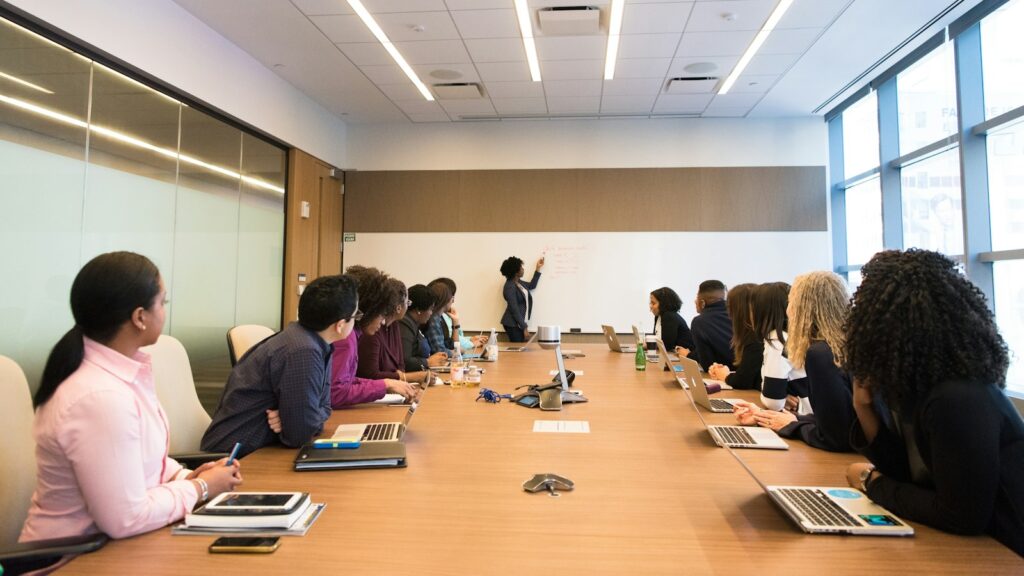 People on conference table looking at talking woman